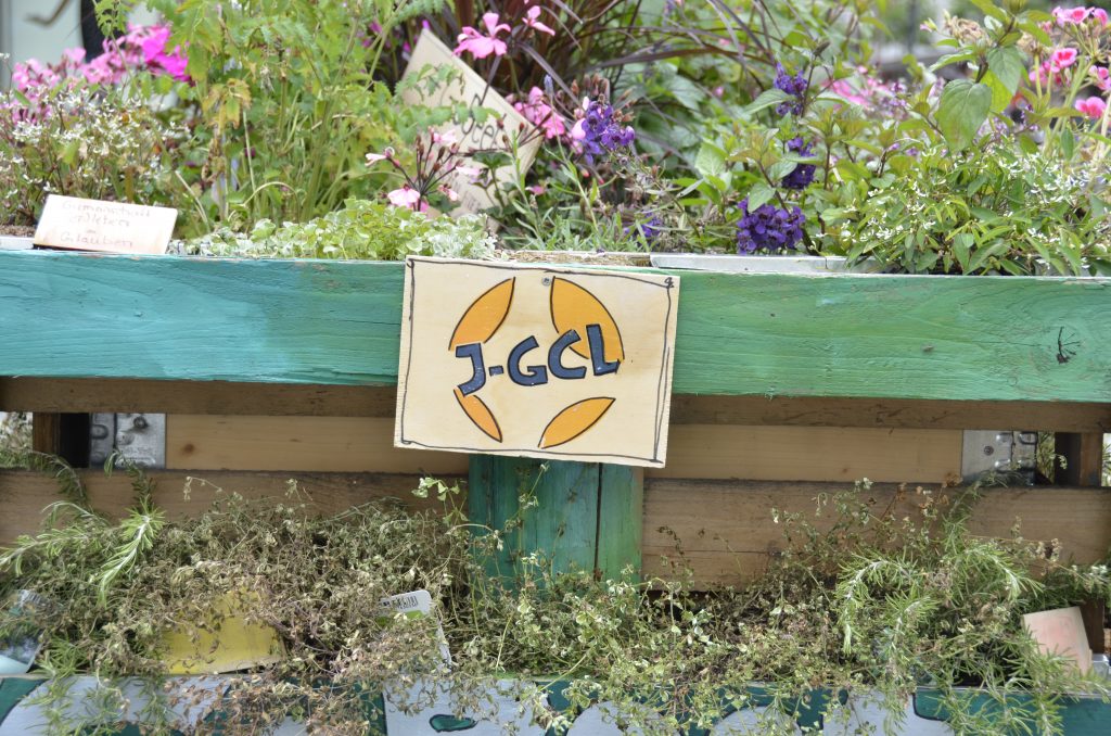 J-GCL-Logo angepinnt an ein Blumenbeet